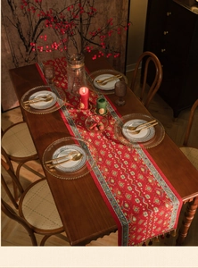 Close-up of red jacquard table runner with ethnic geometric patterns and gold tassels