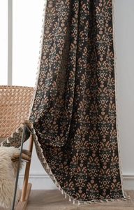 Detail of black floral jacquard curtain fabric featuring white tassel fringe accents
