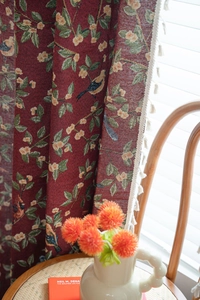 Close-up of red jacquard fabric with bird flower patterns and white fringe tassels