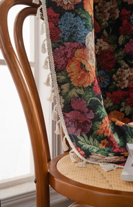 Detailed view of floral jacquard woven fabric with fringes on a wooden chair