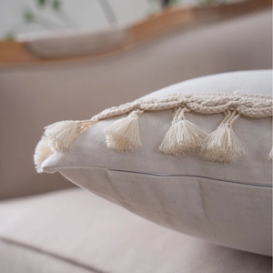 Minimalist beige solid color throw pillow case with tassels and woven fringe detail