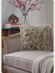 Detail of American vintage floral pillow with fringe trim on a French armchair
