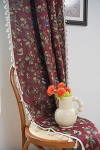 Detailed bird and leaf jacquard pattern on red festive fabric with white fringe trim