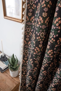 Close-up of black floral woven throw with pink flowers and cream tassel trim detail
