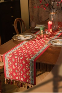 Detail of red table runner with geometric jacquard pattern and colorful tassels for weddings