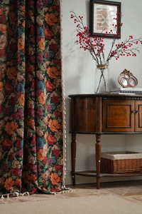 Detail of vintage floral jacquard curtain with white fringe tassels in a home setting