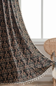 Close-up of black floral curtains with pink flowers and handmade white tassel edges
