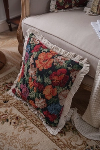 Close-up of floral jacquard throw pillow with decorative fringe on a cozy armchair