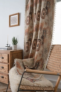 Detail of coffee ring jacquard curtain with tassels draped over a vintage wicker chair