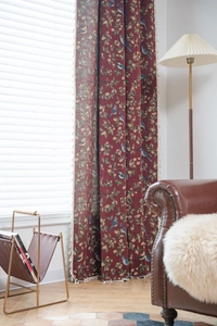 Detailed view of red floral curtains with bird patterns and decorative white tassels