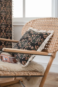 Close-up of black floral jacquard fabric with pink flowers and decorative fringe tassels
