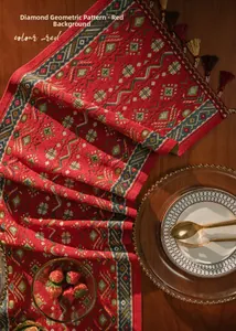 Detail of red table runner with geometric diamond patterns and tassels on wooden desk