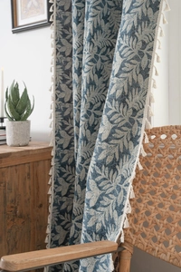Detail of blue jacquard leaf pattern curtain with white cotton fringe tassels and linen texture