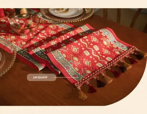Detailed close-up of red geometric jacquard table runner with decorative tassel trim
