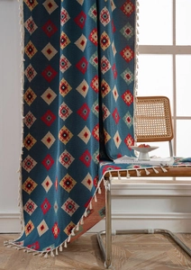 Detail of blue geometric jacquard fabric with bohemian tassels on a textured curtain