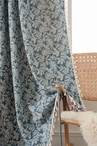 Detailed close-up of blue tropical leaf pattern fabric with white fringe tassel trim