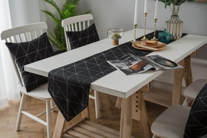 Detail eines geometrischen schwarz-weißen Tischläufers mit passendem Kissen im Haus
