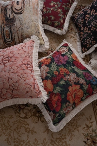 Close-up of jacquard throw pillows with vintage floral patterns and white fringe tassels
