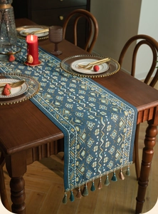 Detail van blauwe tafelloper met etnisch jacquardpatroon en kleurrijke kwastjes eraan