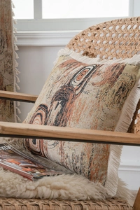 Detailed view of bohemian jacquard pillow with tassel edges on a vintage armchair
