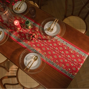 Close-up of red jacquard table runner with geometric patterns on a wooden dining table