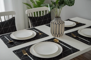 Detailansicht moderner geometrischer Tischläufer mit goldgerandeten Tellern und Besteck