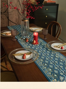 Detail van blauwe tafelloper met geel jacquard patroon op een houten tafelblad