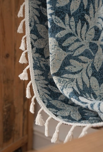 Macro detail of blue floral jacquard fabric texture with decorative cotton tassels
