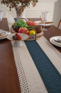 Detail of navy blue and cream woven table runner with boho tassels on wood table