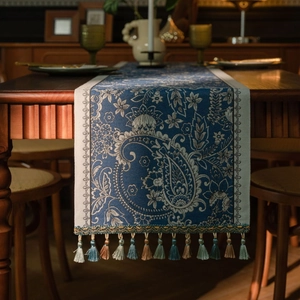 Detail of blue paisley jacquard table runner with decorative colorful fringe tassels
