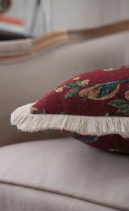 Detailed view of red jacquard cushion with floral bird pattern and soft cream tassels