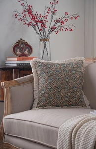 Detail of jacquard floral cushion with fringed edges on a minimalist cream sofa