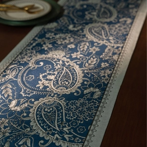 Macro detail of blue paisley jacquard table runner with silver floral weave and wavy edges