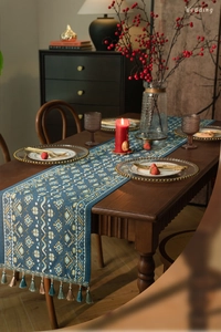 Gedetailleerde weergave van blauwe tafelloper met geometrische patronen en kwast