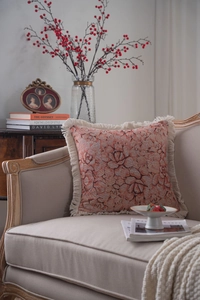 Detail of orange floral jacquard throw pillow with white decorative fringe tassels