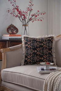 Close-up of floral jacquard throw pillow with cream fringe on vintage armchair