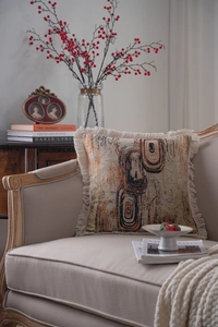 Detail view of woven pillow fringe and abstract pattern on gray fabric sofa