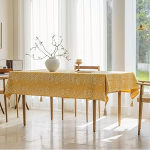 Detailed view of cream jacquard tablecloth with white paisley patterns and corner tassels