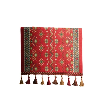 Red table runner with geometric cross patterns and decorative fringe tassels for home decor