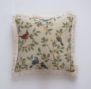 Detailed view of jacquard floral bird cushion featuring birds on branches and fringe trim