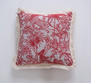 Detail of red jacquard throw pillow with leopard patterns and cream fringe tassels