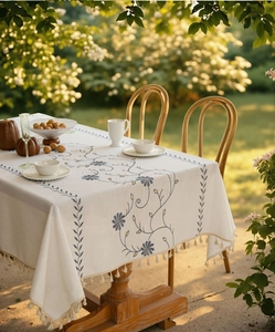 Dettaglio ricamo floreale blu su tovaglia in cotone e lino con bordi di nappe eleganti
