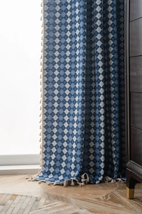 Close-up of blue plaid curtain featuring decorative beige fringe and woven texture