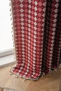 Detail of red and white checkered jacquard fabric with elegant cream fringe tassels