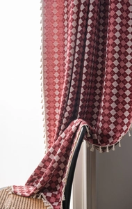 Detail of red and white diamond patterned curtain fabric with ivory tassel fringe edges