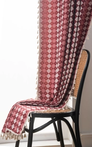 Close-up of red and white bohemian jacquard fabric with elegant cream fringe tassels