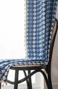 Detail of blue and white diamond pattern curtain fabric with fine cream tassels