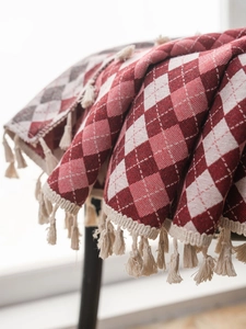 Close-up of red and white diamond jacquard fabric with cream handmade tassel details