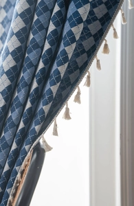 Close-up of blue and white checkered curtains with decorative white fringe tassels
