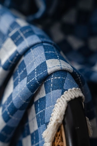 Macro shot of blue and white checkered jacquard fabric with elegant white tassel fringe